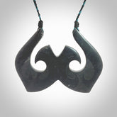 A hand carved large New Zealand Argillite double Hook, Matau, necklace. The cord is a black and blue coloured and is adjustable in length. A large sized hand made double hook necklace by New Zealand artist Rueben Tipene. One off work of art to wear.